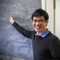 Zhanhong Jian smiles and points back to chalkboard with equation on it